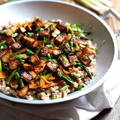 A pot filled with crunchy colorful veggies, golden brown tofu, stir fry sauce.